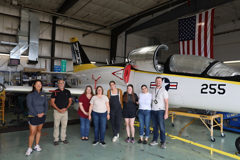 A tour group in front of a jet in the OPL hangar