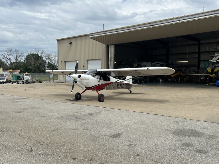 Prop plane parked on pavement outside hangar