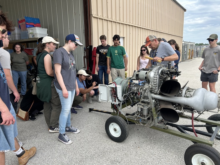 A group of people examine inside of machinery 