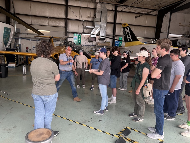 A group of people face each other inside hangar