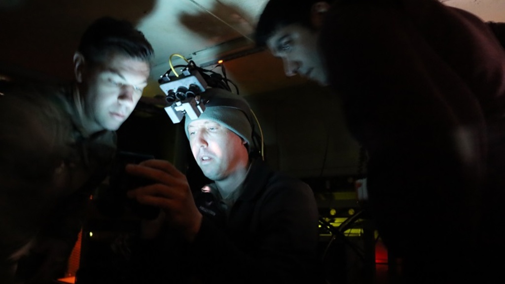 Three people looking at a device inside a cockpit