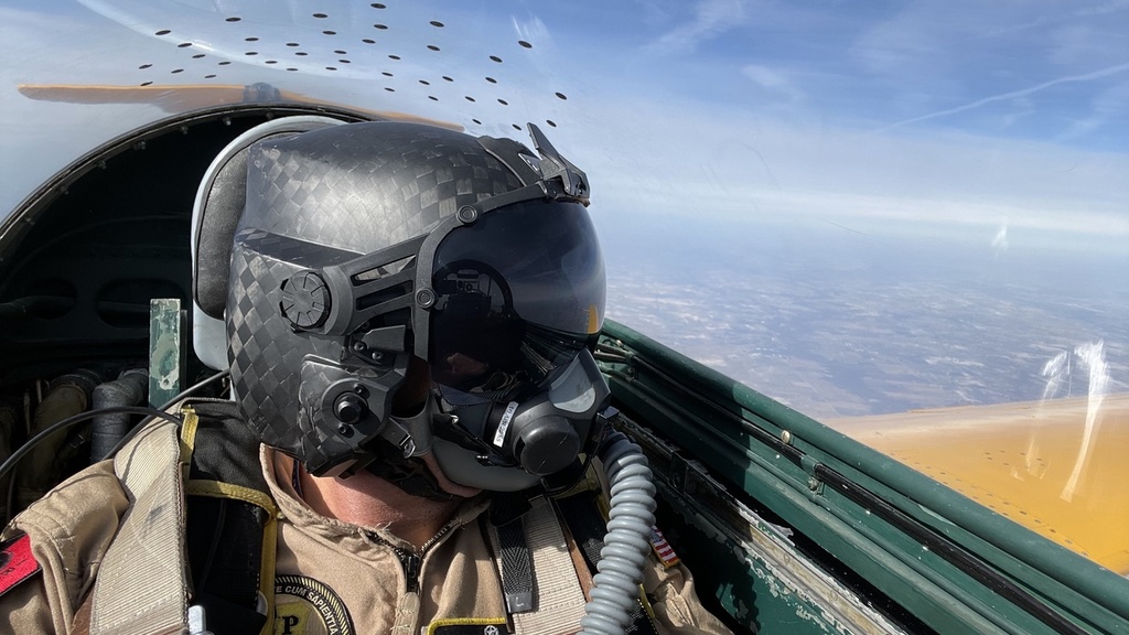 A pilot wearing a helmet in a cockpit while in the air